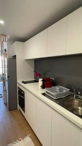 努美阿F1 standing vue mer Anse Vata的厨房配有白色橱柜和水槽
