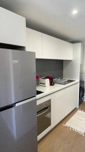努美阿F1 standing vue mer Anse Vata的厨房配有白色橱柜和不锈钢冰箱
