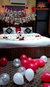 HeṭauḍāHotel Suryansh Pvt Ltd的一组红色和白色的气球,在床边的地板上