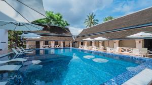 琅勃拉邦JingLand Hotel Luangprabang的一个带白色椅子和遮阳伞的游泳池