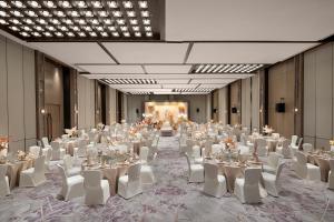 上海上海大华锦绣皇冠假日酒店的一个带白色桌子和白色椅子的大型宴会厅