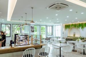 大城RUS Hotel&Convention Ayutthaya的餐厅设有白色的桌椅和窗户。