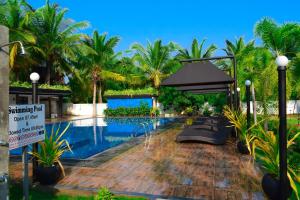 亭可马里绿色花园酒店的一座棕榈树游泳池,旁边有一个标志