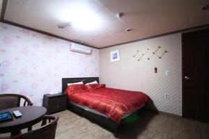 釜山Shine Motel的一间卧室配有红色的床和一张桌子