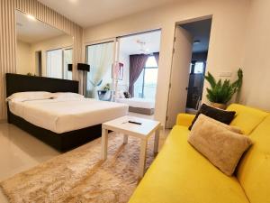 哥打京那巴鲁The Shore Kota Kinabalu City Centre by LW Suites的一间卧室配有一张床和一张黄色的沙发