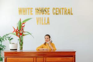 会安White House Central Villa的坐在桌子旁的女孩在电话上说话
