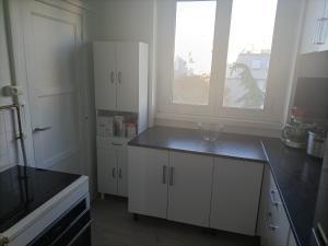 吕埃尔-马尔迈松Appartement cosy 6 personnes proche gare的一间厨房,配有白色的橱柜和大窗户