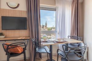 阿尔隆Appart'City Classic Arlon - Porte du Luxembourg的客房设有桌椅和窗户。