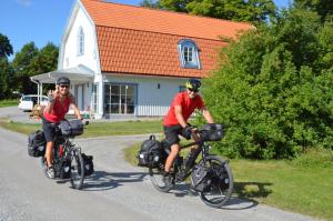 恩雪平Jädra Gårdshotel的两个人骑着自行车沿着房子前面的道路行驶
