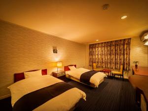 松山Yukai Resort Dogo Saichoraku的酒店客房设有两张床和窗户。