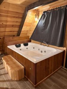 特拉布宗VİRA TAŞ KONAK的木制客房内的按摩浴缸,配有窗帘