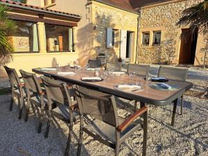维特拉克La Barde Montfort, votre maison d'hôtes à 4 kms de Sarlat Dordogne的一张长桌子,上面有椅子和眼镜