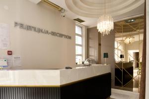 诺维萨德阿尔塔加尔尼精品酒店的大堂设有白色柜台和吊灯。