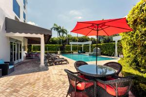 沃思湖沃思湖 - 收费公路 - 西棕榈滩汉普顿酒店的一个带桌子和遮阳伞的庭院,毗邻一个游泳池