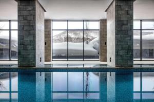 二世古Park Hyatt Niseko Hanazono的一座游泳池,位于一座带窗户和雪的建筑中