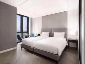 首尔Sofitel Ambassador Seoul Hotel & Serviced Residences的卧室配有一张白色大床和一张书桌