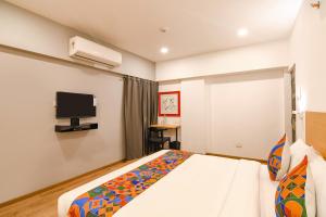 加尔各答FabHotel Sayeeda International的一间卧室配有一张床和一台平面电视