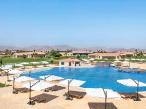 沙姆沙伊赫Rixos Golf Villas And Suites Sharm El Sheikh的一个带白色遮阳伞和椅子的大型游泳池