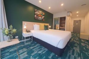 奥克兰La Quinta by Wyndham Ellerslie Auckland的酒店客房设有一张白色大床和一张桌子。