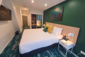 奥克兰La Quinta by Wyndham Ellerslie Auckland的一间卧室设有一张大床和绿色的墙壁