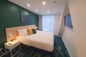奥克兰La Quinta by Wyndham Ellerslie Auckland的一间卧室设有一张大床和绿色的墙壁