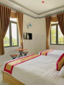 Lien SonLak village的一间卧室设有两张床、一张桌子和窗户。