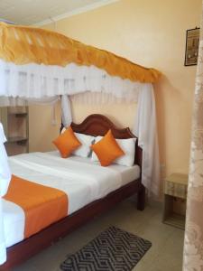 纳库鲁Allamanda Gardens Resort的一间卧室配有带橙色和白色枕头的天蓬床
