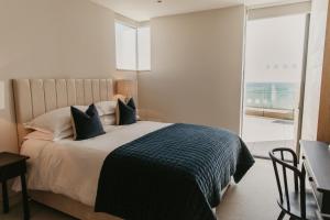 波特兰Clifftops Lodge的一间卧室配有一张带蓝色枕头的床和一扇窗户。