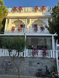 王子岛群hi HOTEL IVY BÜYÜKADA的站在鲜花盛开的房屋阳台上的人