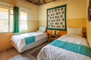 卡萨内African Sunsets (Bophirimo Self-Catering Guest House)的一间卧室设有两张床和两个窗户。
