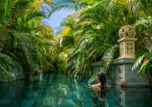 阿德耶Royal River, Luxury Hotel - Adults Only的坐在棕榈树水中的女人