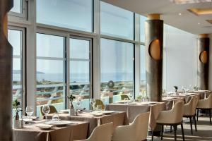 阿尔宗Miramar La Cigale Hotel Thalasso & Spa的餐厅设有桌椅和大窗户。