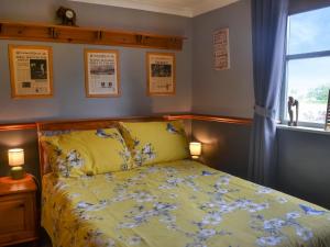科廷厄姆Second Cottage的一间卧室配有一张带黄色棉被的床和窗户
