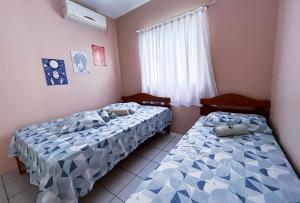 瓜尔达恩巴Pousada Águas do Embaú的两张床位于带窗户的房间内