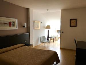 卡卡韦洛斯Hotel Villa de Cacabelos的一间卧室,卧室内配有一张床和一把椅子