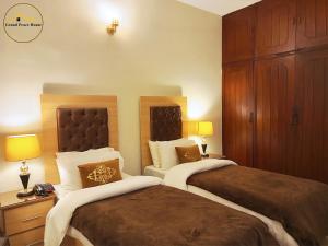伊斯兰堡Grand Peace House I的酒店客房设有两张床和两盏灯。