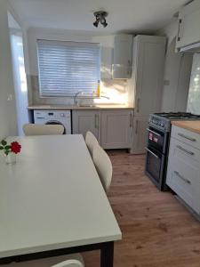 克劳利GATWICK HOUSE的厨房配有白色橱柜和桌椅