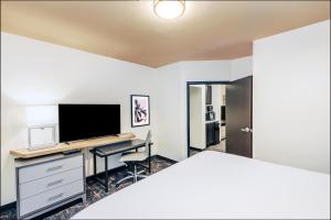 斯蒂尔沃特斯蒂尔沃特大学西假日酒店及套房的一间卧室配有一张床和一张书桌及电视