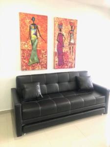 布埃纳文图拉Apartamento Buenaventura的墙上有两幅画作的房间的一张黑色沙发