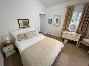 法弗舍姆Little Owl Cottage的卧室配有白色的床和镜子