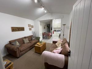 法弗舍姆Little Owl Cottage的客厅配有2张棕色沙发和1张桌子