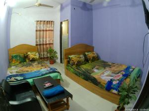 达卡Hotel Rongdhanu Residential的一间卧室配有两张床、一张桌子和一把椅子