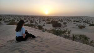 杜兹Private Camp25km-from DOUZ的坐在沙丘上的女人,看着日落
