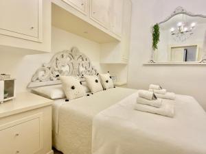 萨萨里LA SUITE DE TURRITAN的一间白色卧室,配有两张床和镜子