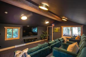 惠斯勒Chalet Whistler - Family Chalet, Hot Tub, BBQ, Cinema, Putting Green - Whistler Platinum的客厅配有绿色沙发和平面电视