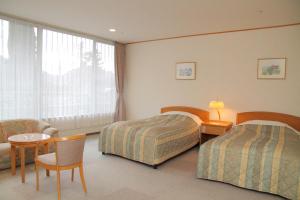 神户有馬 瑞宝園的酒店客房,设有两张床和一张桌子及椅子