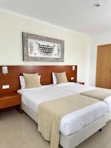 卡尔达斯达·赖尼亚欧亚酒店的卧室配有两张床,墙上挂着一幅画
