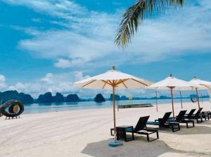 Royal Beach Villa Sonasea Vân Đồn Quảng Ninh的海滩上的一组椅子和遮阳伞