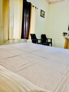 莫尔吉姆Vyana villa rooms的一张白色的大床,位于带两把椅子的房间