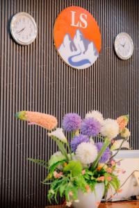 万荣Lisha Roungnakhone Hotel的花瓶在桌子上,墙上挂着时钟